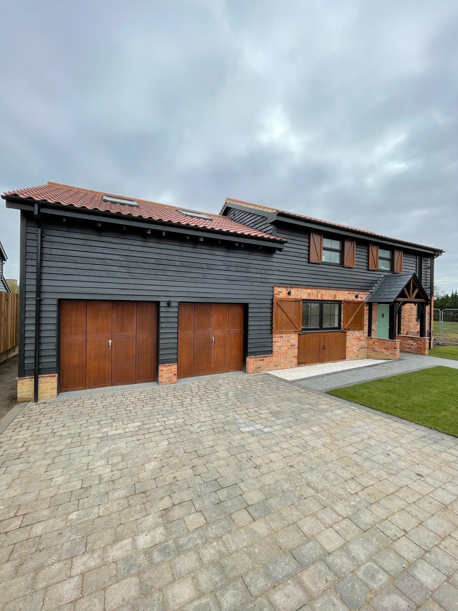 Barn cladding: black boarding installed with timber garage doors and fresh trim