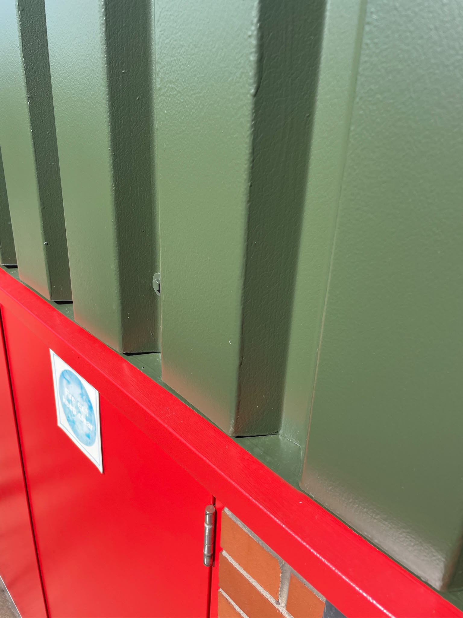 Cladding spraying detail: crisp panel lines where green cladding meets a red sprayed door