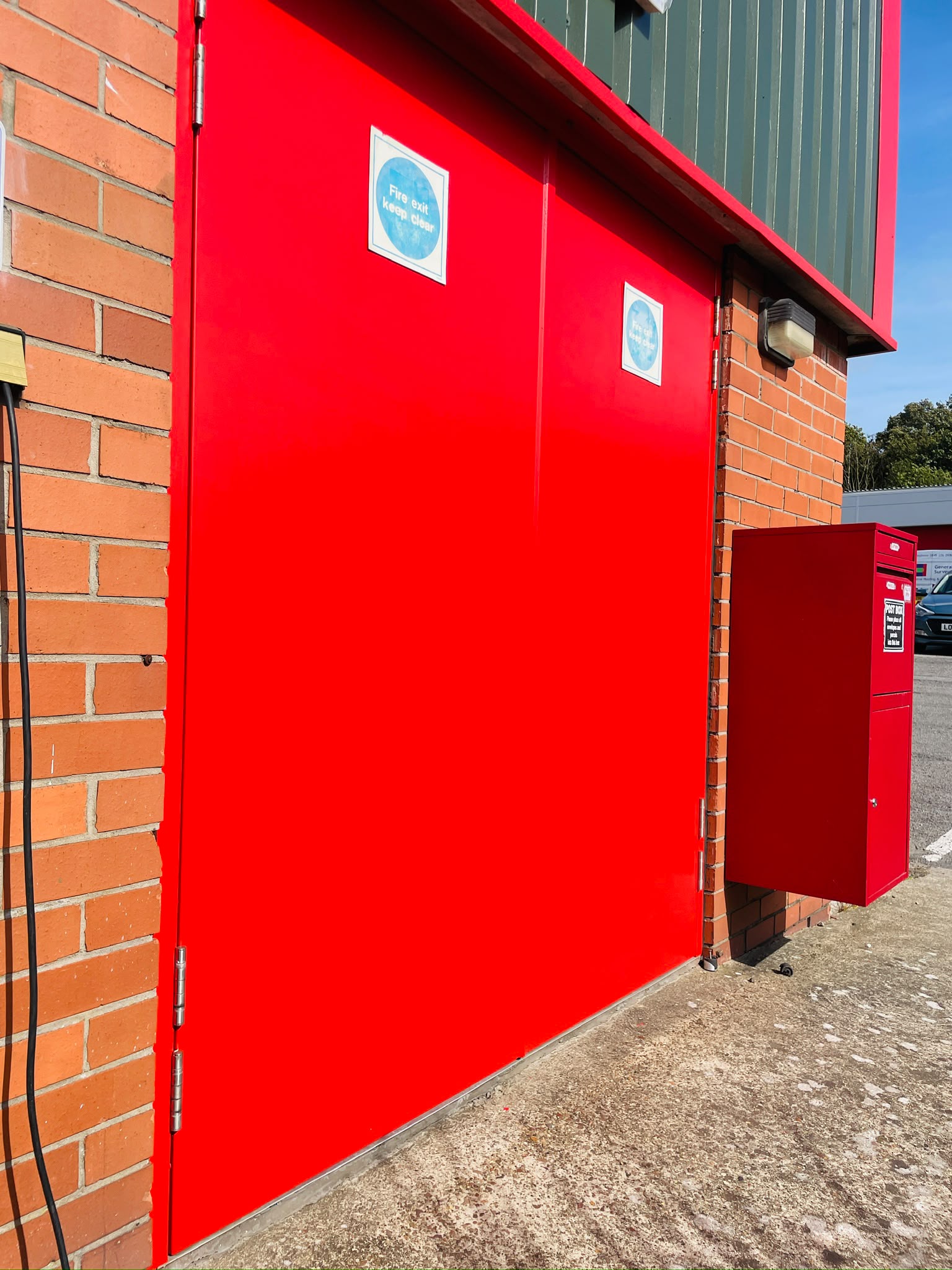 Commercial door spraying: personnel doors recoated hard wearing red on a brick elevation