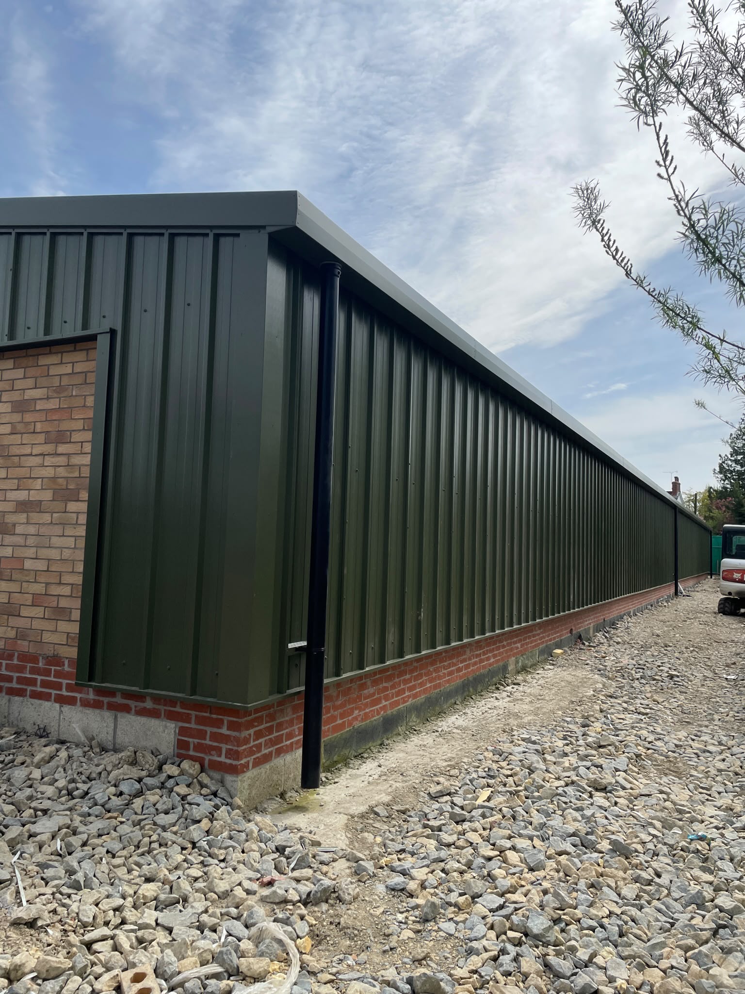 Commercial cladding spraying: long factory elevation resprayed to an even green factory finish