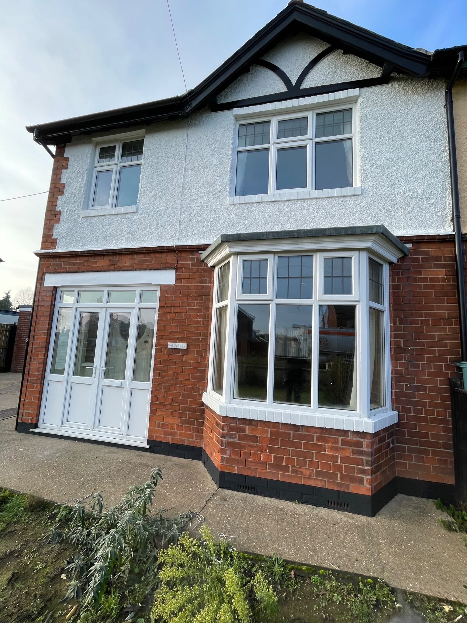 Home exterior spraying: stone render sprayed white with black fascias, soffits and new guttering