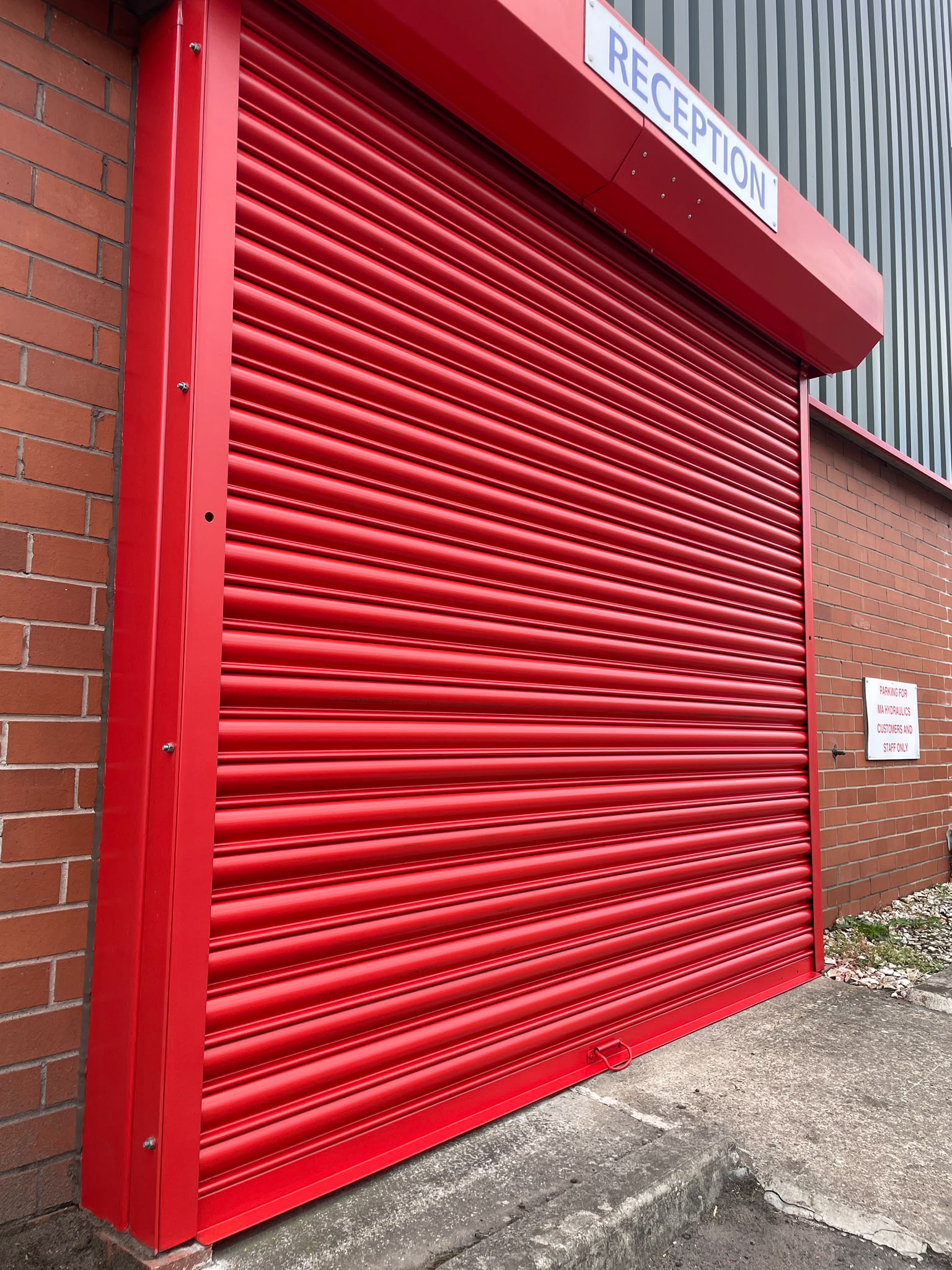 Roller shutter spraying: reception shutter and surround recoated signal red on a commercial unit